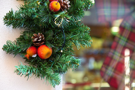 A Christmas wreath with pine cones and berries hangs on a wallの写真素材