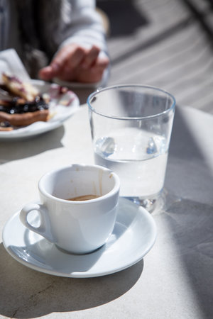 There is a cup of coffee and a glass of water placed neatly on a tableの写真素材