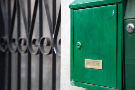 A greenpainted mailbox can be found next to a wrought iron gateの写真素材