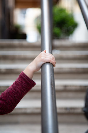 A person is holding onto a metal railing on a set of stairs