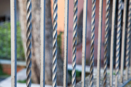 Closeup of a wrought iron fence with a blurry backgroundの写真素材