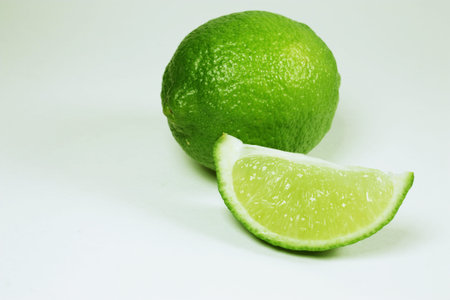 Whole lime with a slice isolated on a white background