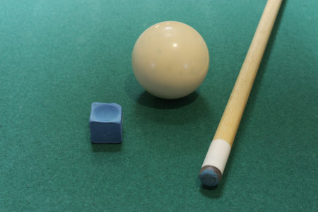 Que ball, stick, and chalk laying on a pool table