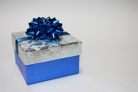 Beautiful holiday present wrapped in silver and blue with a blue bow.の写真素材
