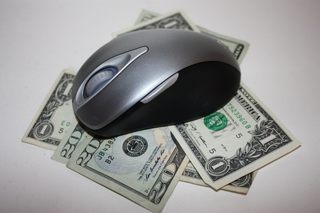 Money with a computer mouse on top to signify online savingsの写真素材
