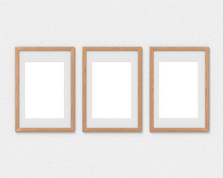 Set of 3 vertical wooden frames mockup with a border hanging on the wall. Empty base for picture or text. 3D rendering.の写真素材