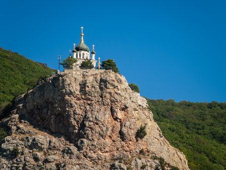 Orthodox Church on a rocky ledge against the background of the sky and mountain forestの写真素材