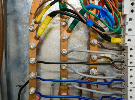 Three-phase copper high-voltage busbar in a metal box with automatic circuit breakers.