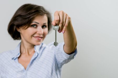 Adult smiling business woman or real estate agent showing keys from new home. Success in the concept of business.の写真素材