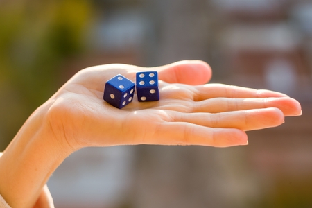 Dice 2 4 in the female hand, sunset background. Gambling devices. Game of chance concept.の写真素材