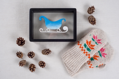 Winter holidays celebrating. Frame with snow-covered sledges, bumps and knitted mittens with ornament.の写真素材