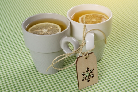 Couple cups of tea with a lemon on the table, a winter symbol-snowflake. Holidays, christmas, winter, food and drinks concept.の写真素材