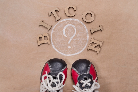 Word bitcoin in abstract letters and question mark. Background of old paper, sneakers. copy spaceの写真素材