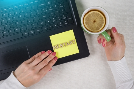 Try Again Restart Retry Persistence Endure Concept. Text Restart, from wooden letters on a paper sticker. Background laptop, woman's hands on the keyboardの写真素材