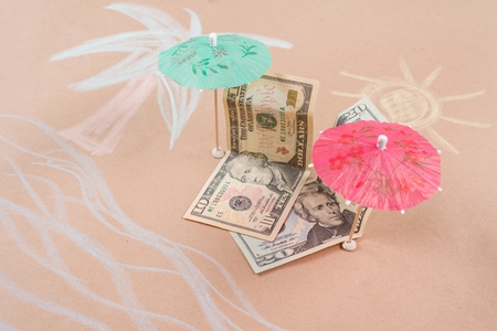 The concept of offshore banking and tax havens. Picture with dollar bills on a tropical beach, under a palm tree and an umbrellaの写真素材