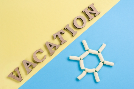 Abstract background image. Word vacation wooden letters on a blue and yellow background, and an abstract sun background.の写真素材