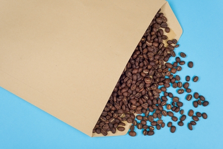 The concept of coffee imports, exporting coffee. Business concept- coffee business On a blue background an abstract envelope with coffee beans. Copy spaceの写真素材