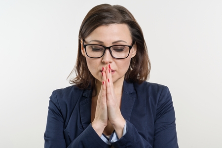 Businesswoman in glasses, closed her eyes and prays, meditates. White backgroundの写真素材