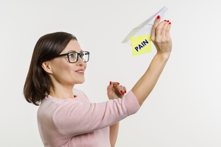 Woman gets rid of pain and remove the problem . Sends a paper abstract airplane with the word Pain.の写真素材