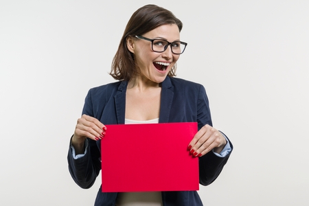 Smiling middle aged woman with red sheet of paper on white backgroundの写真素材