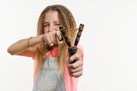 Naughty girl teenager with curly hair holds a slingshot. White Background Studioの写真素材