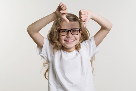 Girl child shows thumb down sign bad, dislike, negative. On white background in white base T-shirt.の写真素材