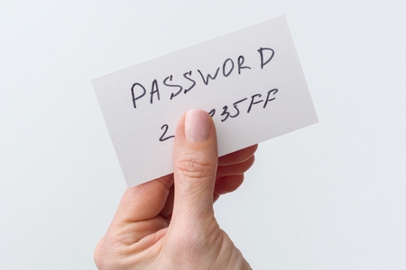 Woman's hand holds a password on paper, that covers the password with finger.の写真素材