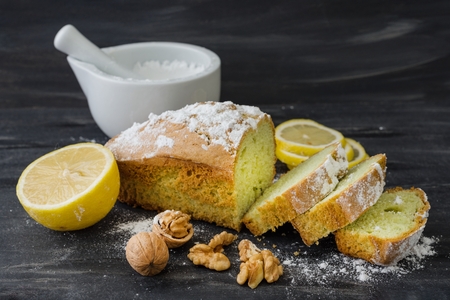 Mint cake on black surface with lemon, nuts, powdered sugar.の写真素材