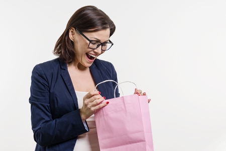 Surprised adult woman looking shopping bag, white background,の写真素材
