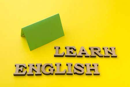Learn English, words in wooden letters with yellow background.