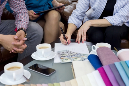 Money, contract, couple and saleswoman in the background. Office showroom interior fabrics, decorの写真素材