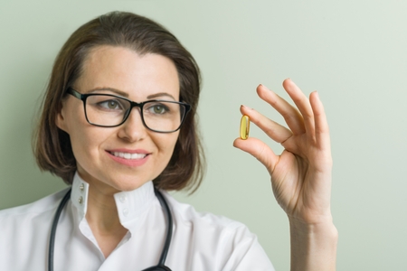Female doctor takes vitamin capsule. Healthy lifestyle, nutritional supplements, vitamin d, e, fish oil capsules.の写真素材