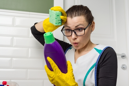 Housewife woman does the cleaning with interest reading the instructions on the detergent.の写真素材