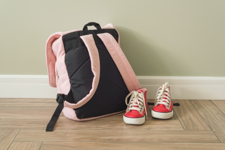 School backpack and sneakers on the floor in a home interiorの写真素材