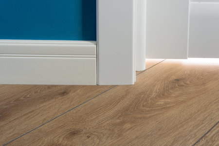 Details in the interior. Laminated parquet floors immitating oak texture, white baseboard, white...