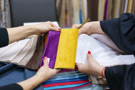 Women watch samples of fabrics for curtains, furniture upholstery in a new houseの写真素材