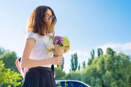 Back to school. Sad teen girl goes first day to school, with backpack, flowers. Copy spaceの写真素材