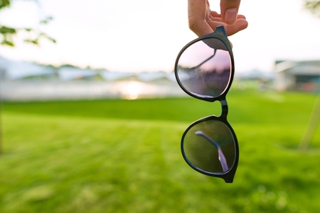 Sunglasses symbol of summer, background horizon with sunset, green lawn. Copy spaceの写真素材