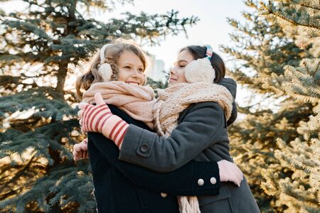 Outdoor winter portrait of two little girls smiling and having fun near the Christmas tree, golden hour.の写真素材