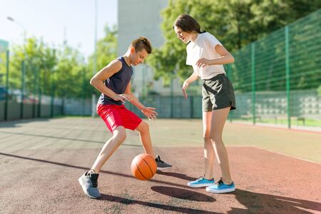 Streetball basketball game with two players, teenagers girl and boy, morning on basketball court.の写真素材