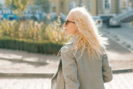 Closeup outdoor portrait of young smiling blond woman with sunglasses with long curly hair. On city street sunny day.の写真素材