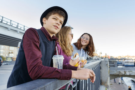 Lifestyle of adolescents, boy and two teen girls are walking in the city. Laughing, talking children...