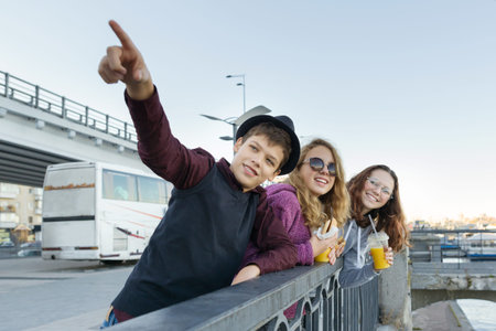 Lifestyle of adolescents, boy and two teen girls are walking in the city. Laughing, talking children...