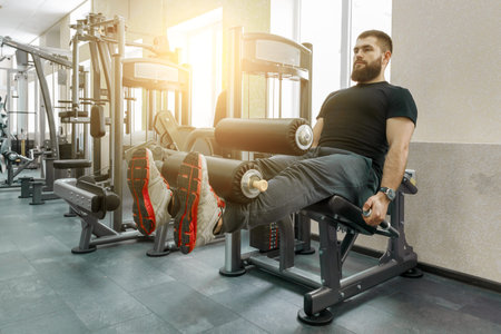 Athletic muscular bearded exercising man at the modern sport gym. Fitness, sport, training, people...