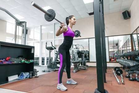Young athletic woman exercising on the machines in modern sport gym. Fitness, sport, training,...