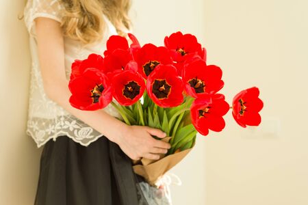 Child girl holding bouquet of red tulips flowers. Gift, surprise, spring family holiday.の写真素材