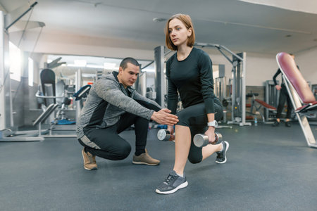 Young woman doing exercises with personal instructor in gym. Sport, athlete, training, healthy...