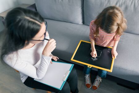 Young female psychologist talking with patient child girl in office. Mental health of children.の写真素材