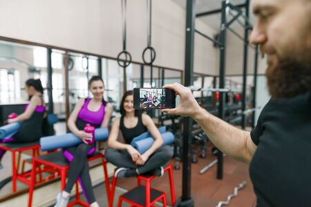 Young athletic smiling woman laughing in the gym, photographed on mobile phone. Fitness, sport, training, people, healthy lifestyle conceptの写真素材