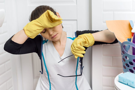 Tired adult woman cleaning bathroom toilet room